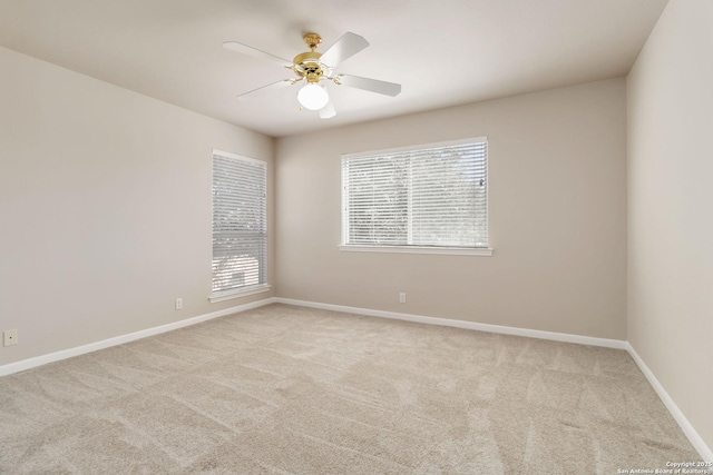 carpeted empty room featuring ceiling fan and baseboards