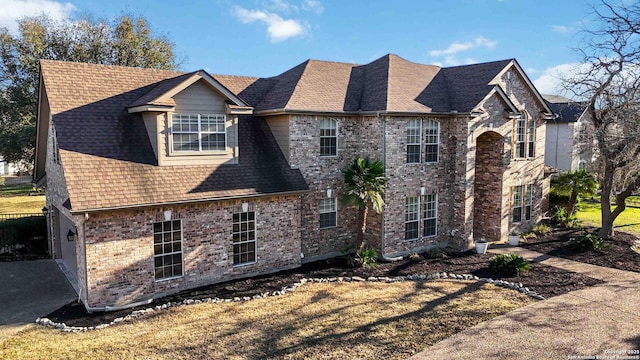 view of front facade featuring a shingled roof and brick siding