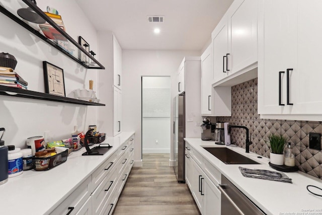 kitchen featuring a sink, visible vents, white cabinetry, backsplash, and open shelves