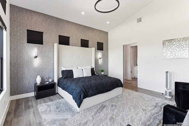 bedroom featuring recessed lighting, an accent wall, wood finished floors, baseboards, and wallpapered walls