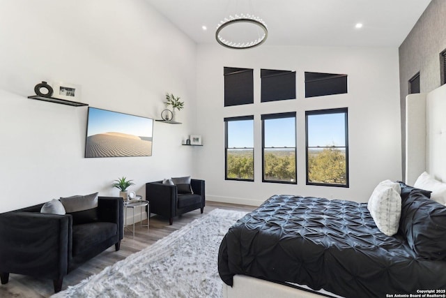 bedroom with a towering ceiling, baseboards, wood finished floors, and recessed lighting