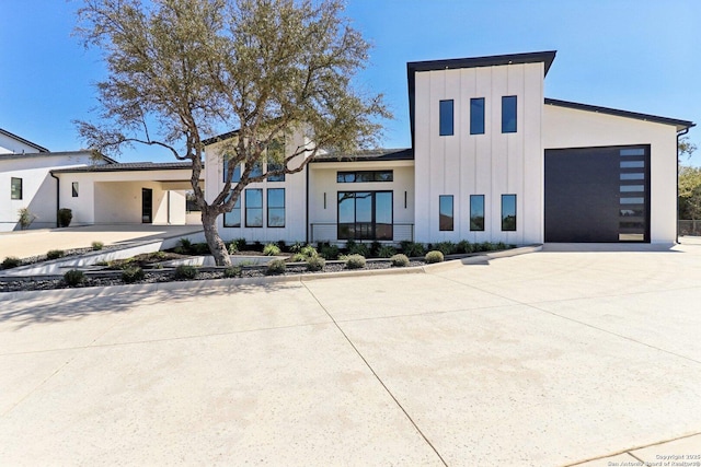 contemporary home with board and batten siding, driveway, and a garage