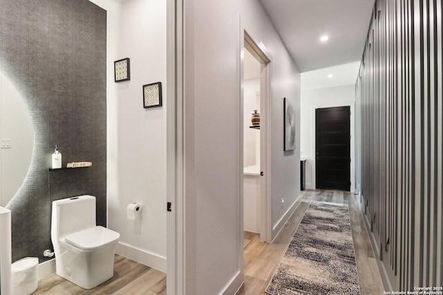 corridor featuring light wood finished floors, recessed lighting, and baseboards