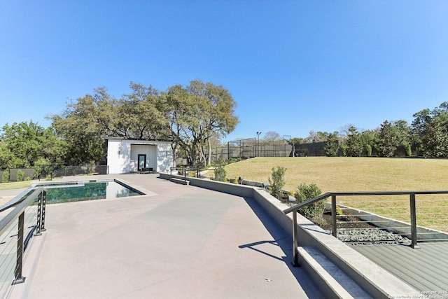 view of swimming pool featuring an outbuilding, a patio area, a lawn, and fence