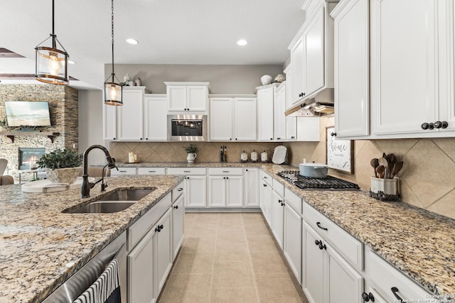 kitchen featuring appliances with stainless steel finishes, white cabinetry, a sink, and under cabinet range hood