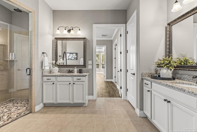 bathroom with a shower stall, visible vents, two vanities, and a sink