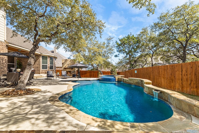 view of pool with a pool with connected hot tub, a fenced backyard, and a patio