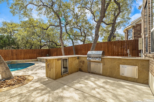 view of patio featuring a fenced in pool, an outdoor kitchen, a grill, a sink, and a fenced backyard