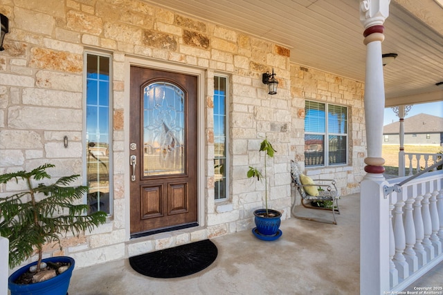 doorway to property with stone siding and a porch