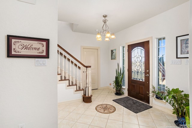 entrance foyer with baseboards, light tile patterned floors, an inviting chandelier, and stairs