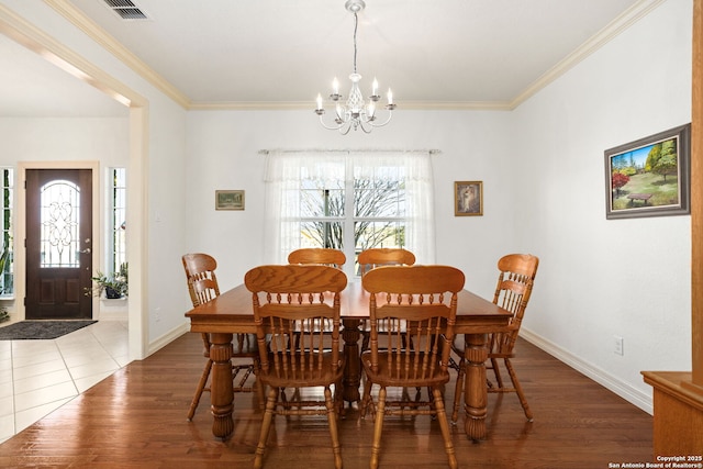 dining space featuring ornamental molding, visible vents, a notable chandelier, and wood finished floors