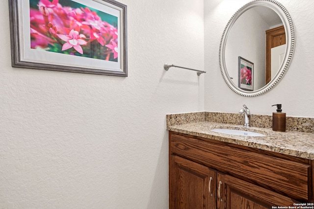 bathroom featuring a textured wall and vanity