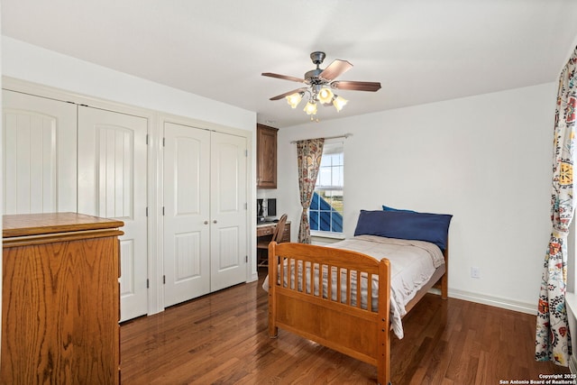 bedroom featuring two closets, ceiling fan, baseboards, and wood finished floors