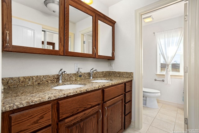 bathroom with double vanity, toilet, a sink, and tile patterned floors