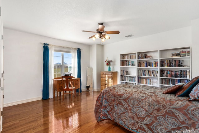 bedroom with a ceiling fan, baseboards, visible vents, and wood finished floors