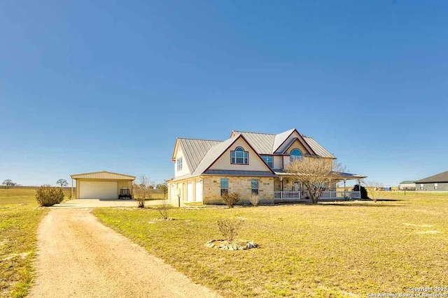 view of front of house featuring an outbuilding, a chimney, a front yard, metal roof, and a garage