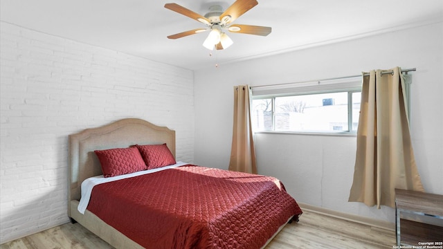 bedroom featuring brick wall, a ceiling fan, and wood finished floors