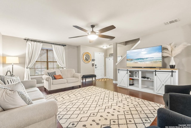 living area with dark wood-style floors, baseboards, visible vents, and a ceiling fan