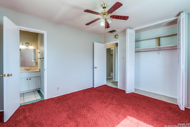 unfurnished bedroom with ensuite bathroom, carpet floors, a sink, visible vents, and a closet