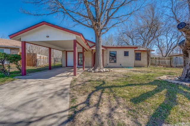 view of front of property featuring brick siding, concrete driveway, a front yard, fence, and a carport