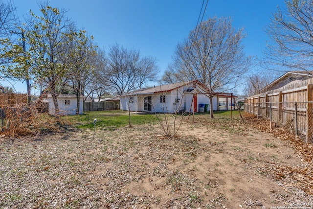 back of property with a fenced backyard and a lawn