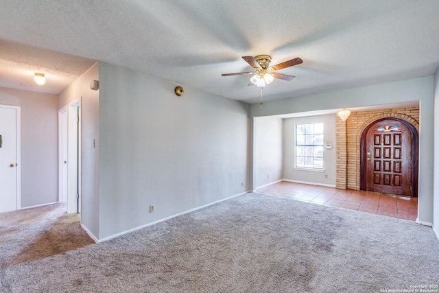 unfurnished living room featuring tile patterned flooring, carpet, a ceiling fan, and a textured ceiling