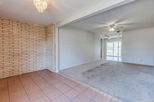 unfurnished room featuring light carpet, light tile patterned floors, brick wall, ceiling fan, and a textured ceiling