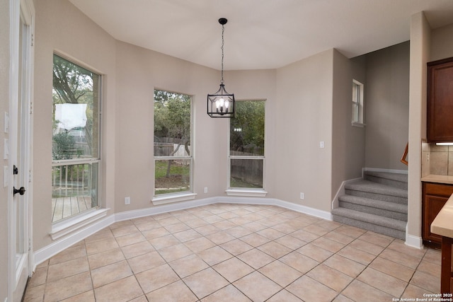 unfurnished dining area featuring baseboards, stairs, a chandelier, and light tile patterned flooring