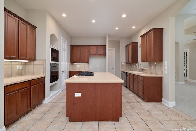 kitchen with light tile patterned floors, a sink, light countertops, brown cabinets, and black appliances