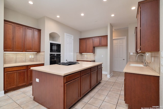 kitchen featuring black appliances, light tile patterned flooring, a sink, and a center island