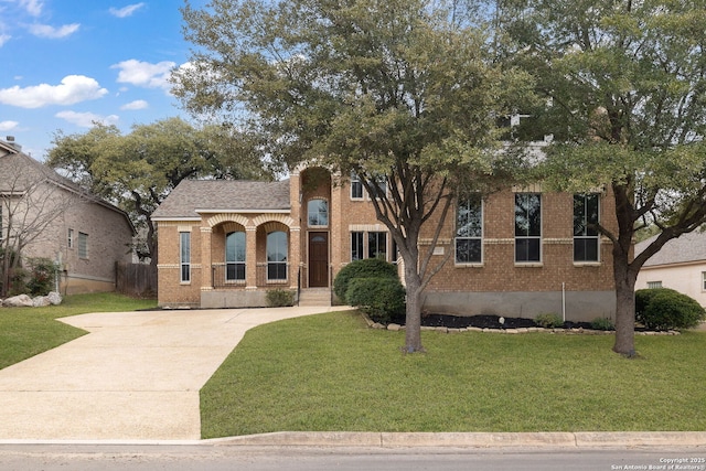 view of front of property featuring a front yard, brick siding, driveway, and roof with shingles