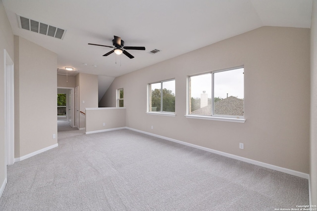 unfurnished room featuring attic access, visible vents, vaulted ceiling, and light carpet