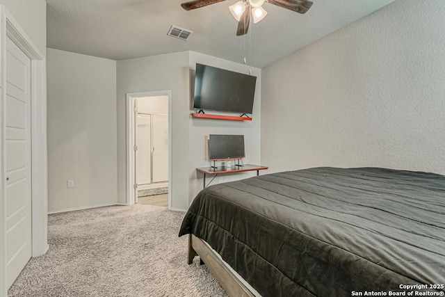 carpeted bedroom with visible vents, a textured wall, ensuite bathroom, a textured ceiling, and baseboards