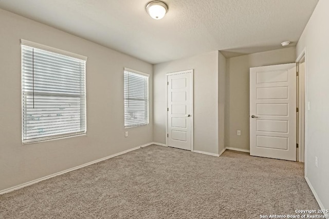 unfurnished bedroom featuring a textured ceiling, a closet, carpet flooring, and baseboards