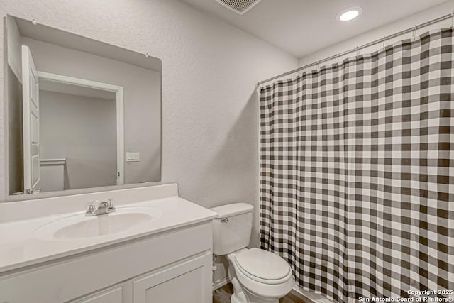 full bathroom with toilet, a textured wall, visible vents, and vanity