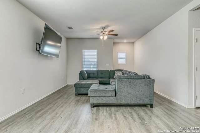 living room featuring light wood-style flooring, visible vents, baseboards, and ceiling fan