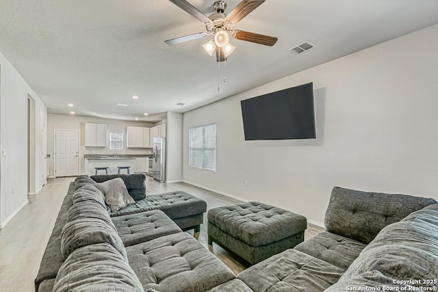 living area featuring visible vents, baseboards, light wood-style flooring, ceiling fan, and recessed lighting