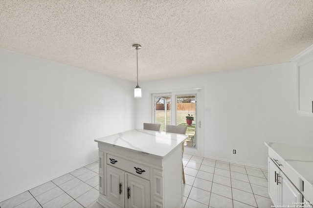 kitchen with a center island, decorative light fixtures, white cabinets, light tile patterned flooring, and a textured ceiling