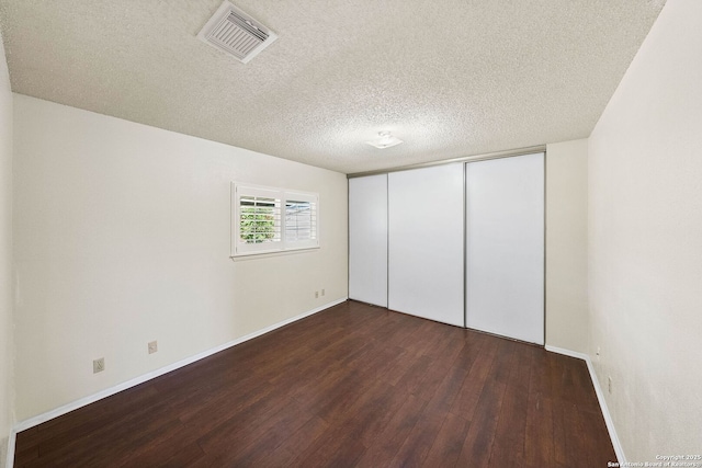 interior space with baseboards, a textured ceiling, visible vents, and wood finished floors