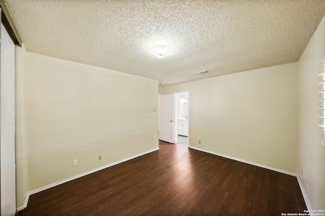 unfurnished room featuring hardwood / wood-style flooring, baseboards, visible vents, and a textured ceiling