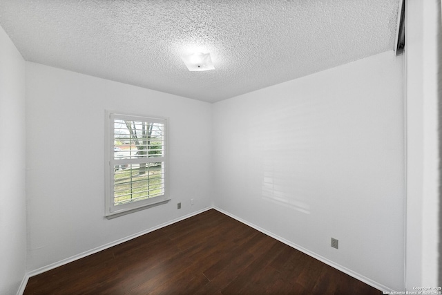 spare room featuring a textured ceiling, dark wood-type flooring, and baseboards