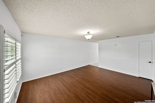 spare room with a textured ceiling, visible vents, and wood finished floors