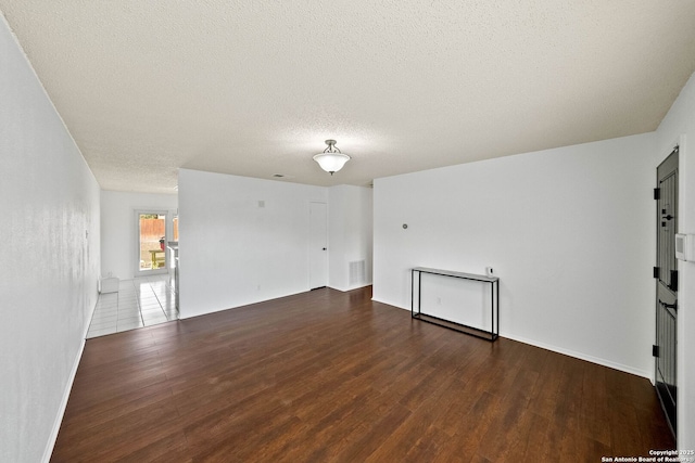 spare room with a textured ceiling, visible vents, and wood finished floors