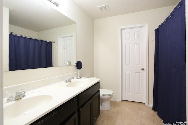 bathroom featuring toilet, double vanity, a sink, and visible vents