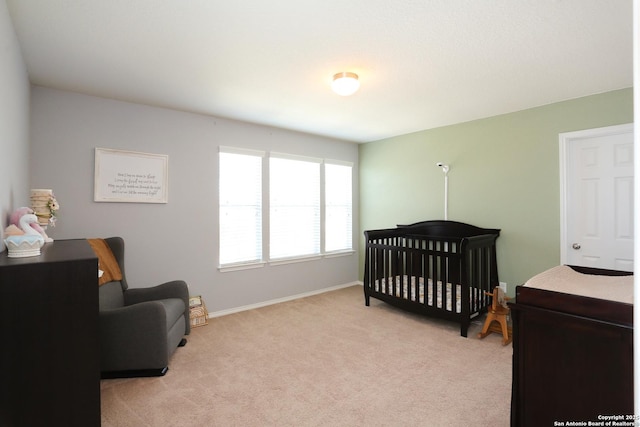 bedroom featuring light carpet, a crib, and baseboards