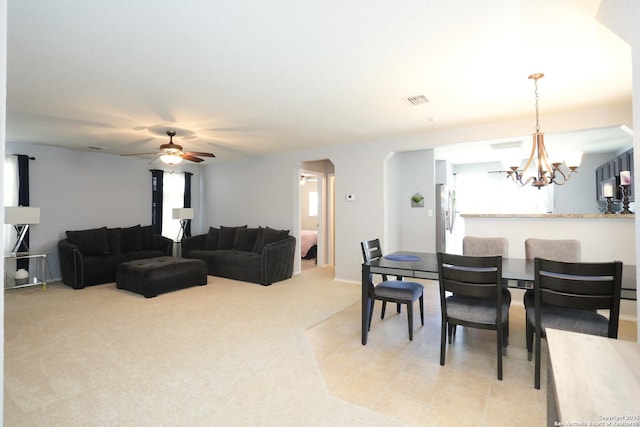 dining area with ceiling fan with notable chandelier, visible vents, arched walkways, and light colored carpet