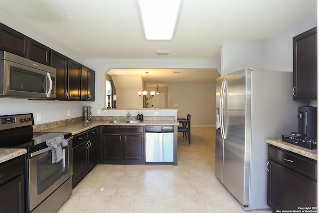 kitchen featuring a notable chandelier, a peninsula, a sink, visible vents, and appliances with stainless steel finishes