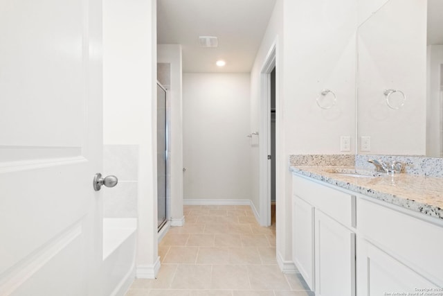 full bathroom featuring a stall shower, baseboards, a garden tub, and vanity