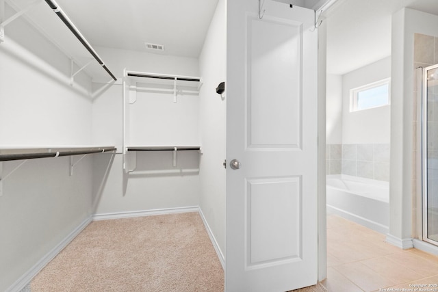 walk in closet featuring carpet floors, visible vents, and tile patterned floors