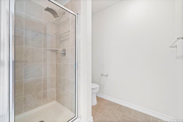 bathroom with a stall shower, baseboards, toilet, and tile patterned floors